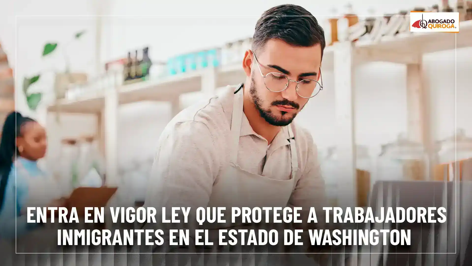 Hombre con gafas y delantal trabajando en un entorno de cocina, con una mujer al fondo.